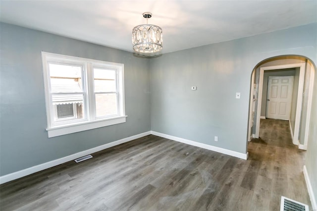 unfurnished room featuring dark hardwood / wood-style floors and an inviting chandelier