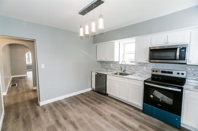 kitchen featuring sink, appliances with stainless steel finishes, tasteful backsplash, light hardwood / wood-style flooring, and white cabinets