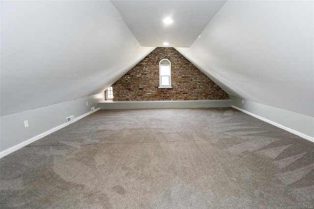 additional living space with brick wall, vaulted ceiling, and carpet