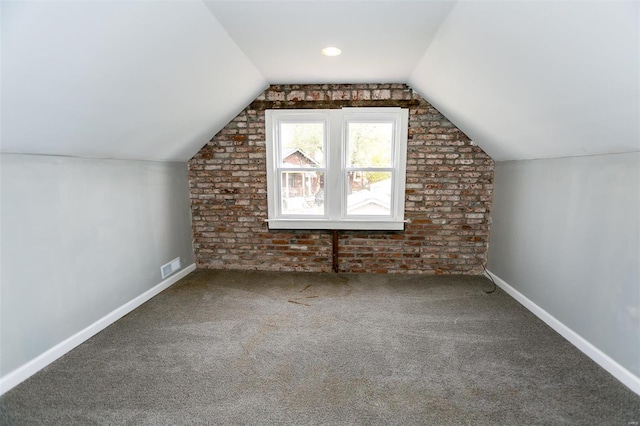 bonus room with carpet floors, brick wall, and lofted ceiling