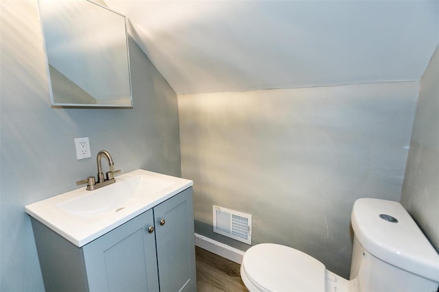 bathroom featuring toilet, vanity, vaulted ceiling, and hardwood / wood-style flooring