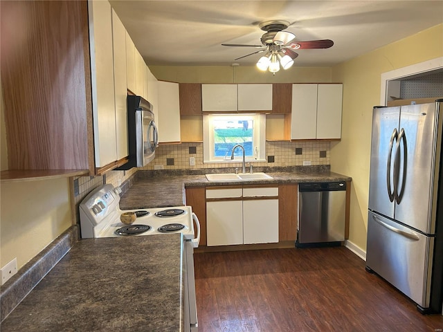 kitchen with appliances with stainless steel finishes, dark hardwood / wood-style floors, decorative backsplash, sink, and white cabinets