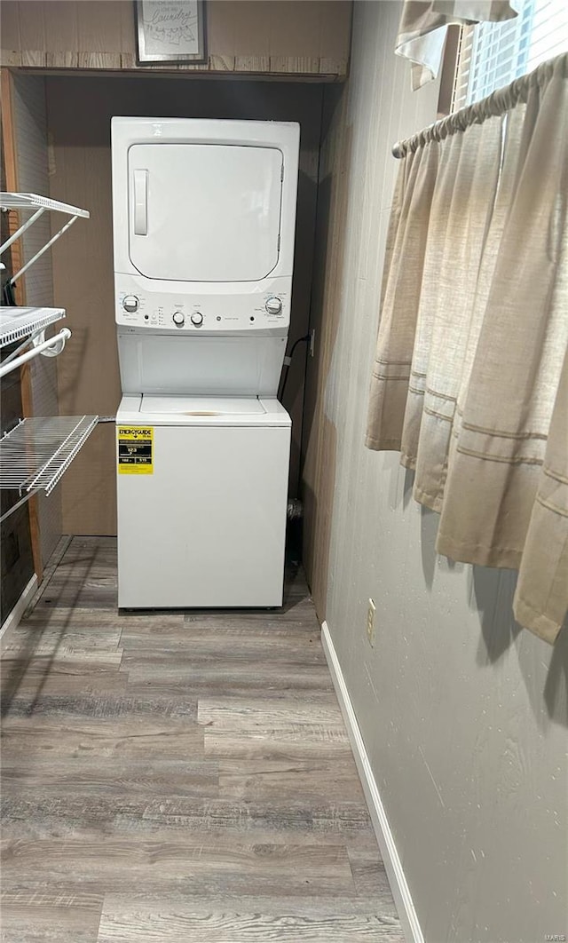 clothes washing area featuring stacked washer and clothes dryer and hardwood / wood-style floors