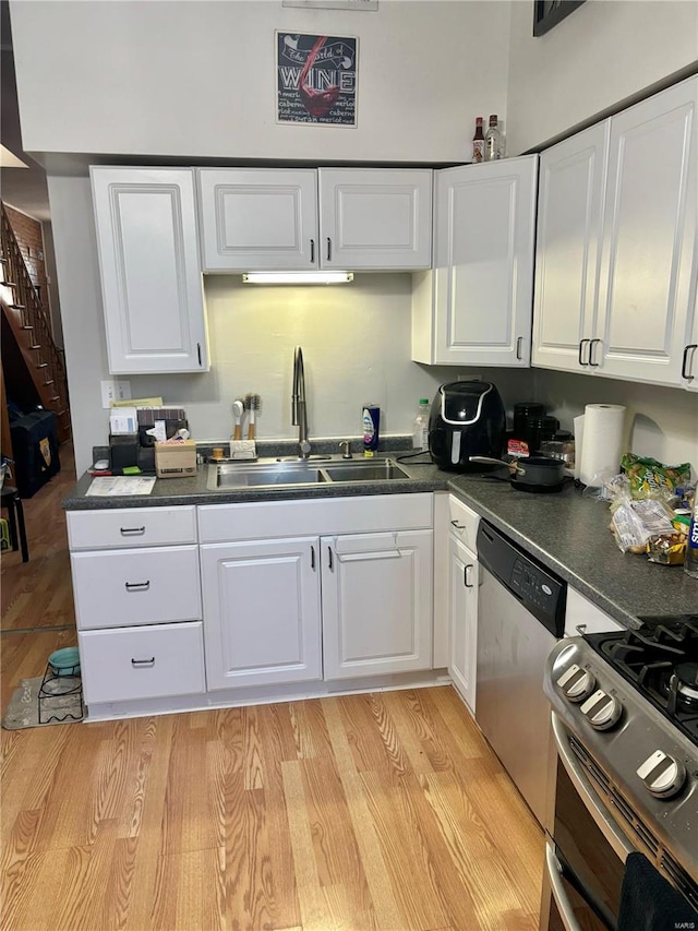 kitchen with light hardwood / wood-style floors, white cabinets, sink, and stainless steel appliances