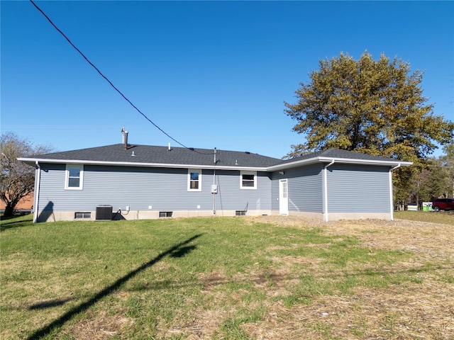 back of house with central AC unit and a yard