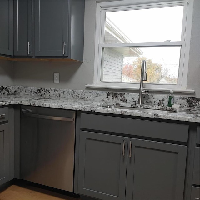 kitchen with light stone countertops, gray cabinetry, sink, and dishwasher