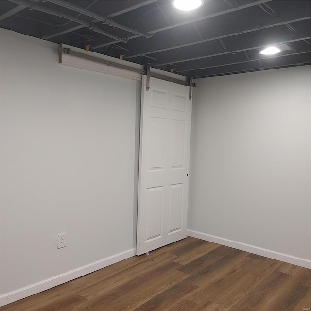 basement with dark hardwood / wood-style flooring and a barn door