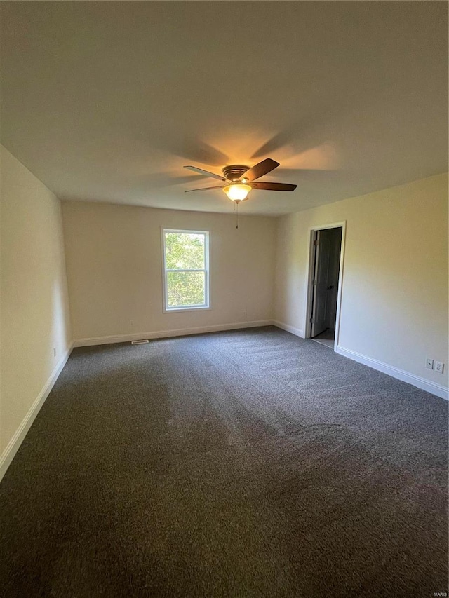 empty room with ceiling fan and dark carpet