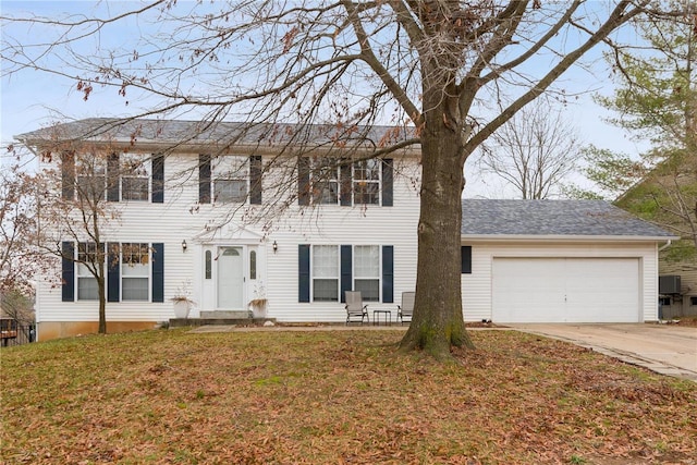 colonial home featuring central air condition unit, a front yard, and a garage