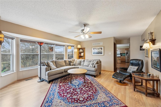 living room featuring a textured ceiling, light hardwood / wood-style floors, and ceiling fan