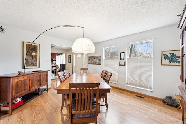 dining area featuring light hardwood / wood-style floors and a textured ceiling