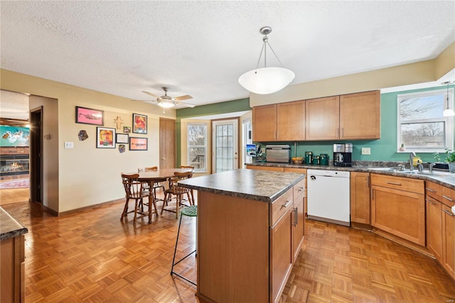 kitchen featuring ceiling fan, a kitchen island, white dishwasher, pendant lighting, and light parquet flooring