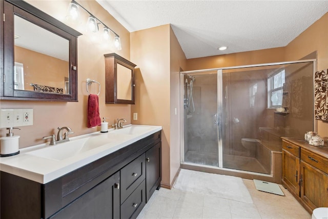 bathroom with tile patterned floors, vanity, an enclosed shower, and a textured ceiling