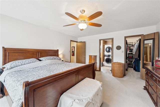 carpeted bedroom with stacked washer and clothes dryer, ceiling fan, a spacious closet, a textured ceiling, and a closet