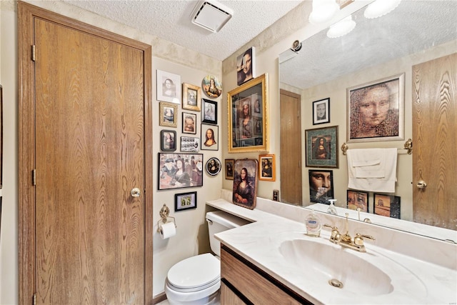 bathroom with vanity, a textured ceiling, and toilet