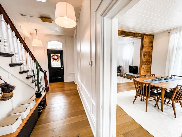 entryway featuring a wealth of natural light, wood-type flooring, and wooden walls