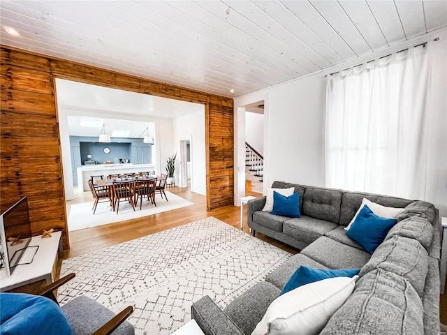 living room with light hardwood / wood-style flooring, wood walls, and wood ceiling