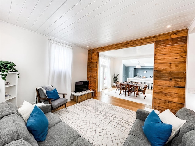 living room featuring wooden ceiling, light hardwood / wood-style floors, wooden walls, and a skylight