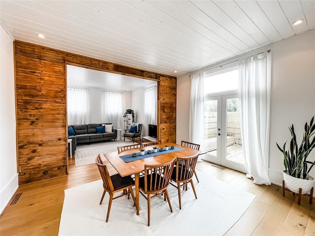 dining area with french doors, light hardwood / wood-style flooring, wooden walls, and wooden ceiling