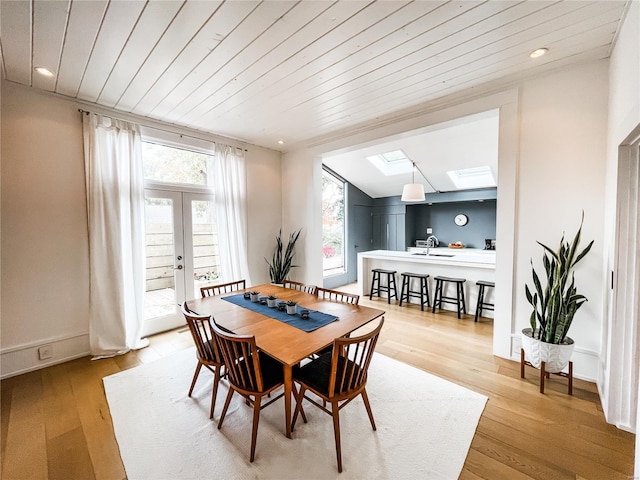 dining space with french doors, sink, a skylight, wooden ceiling, and light hardwood / wood-style flooring