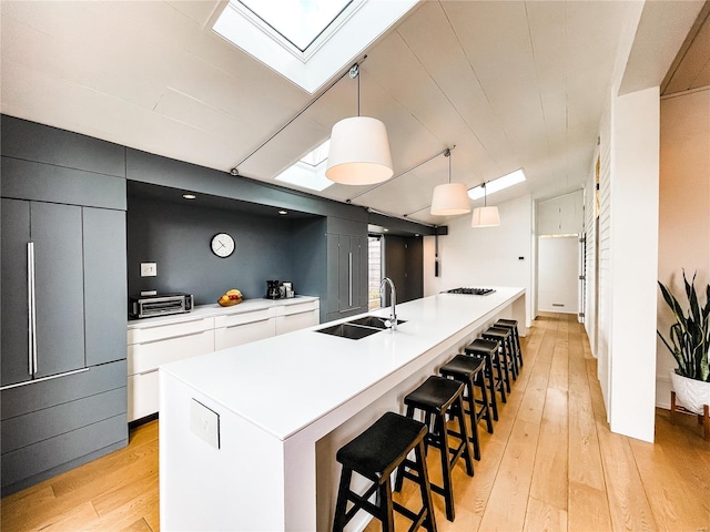 kitchen featuring pendant lighting, sink, light hardwood / wood-style floors, and a spacious island