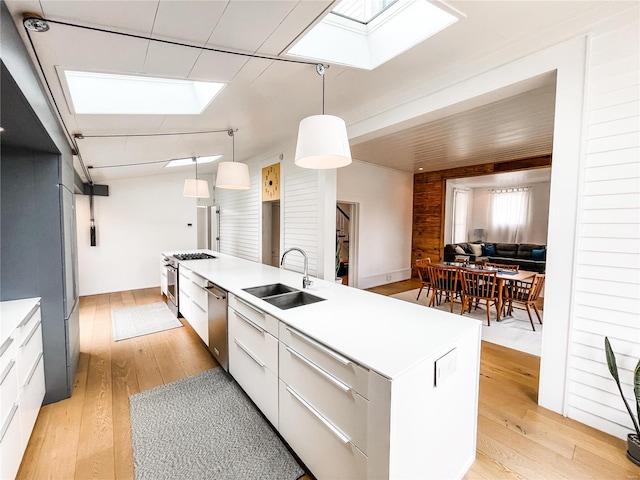 kitchen with white cabinets, hanging light fixtures, a skylight, a kitchen island, and light wood-type flooring