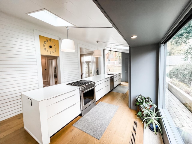 kitchen featuring a kitchen island, light wood-type flooring, appliances with stainless steel finishes, pendant lighting, and white cabinets