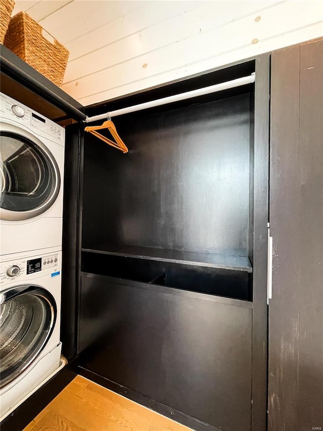 washroom featuring stacked washing maching and dryer and light hardwood / wood-style flooring