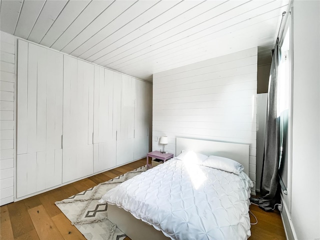 bedroom featuring dark hardwood / wood-style flooring and wooden walls