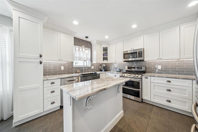 kitchen featuring backsplash, a center island, stainless steel appliances, white cabinets, and light stone countertops