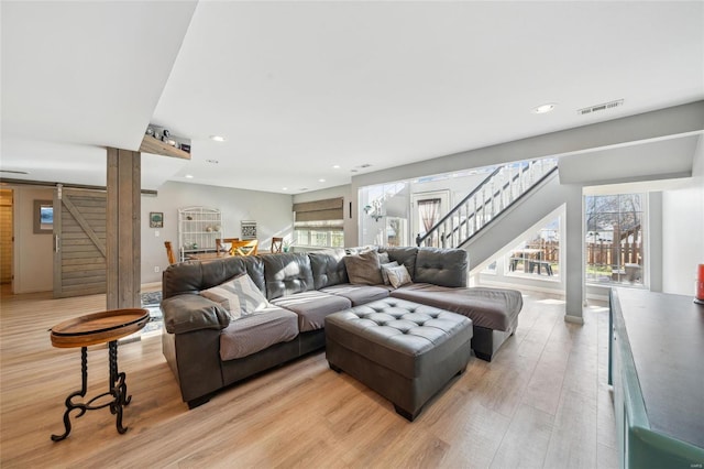 living area featuring visible vents, a healthy amount of sunlight, light wood-type flooring, and stairs