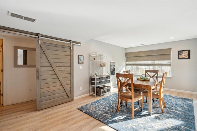 dining room featuring wood finished floors, visible vents, baseboards, recessed lighting, and a barn door