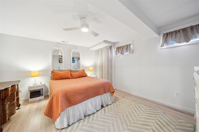 bedroom with ceiling fan, baseboards, arched walkways, and light wood-style flooring