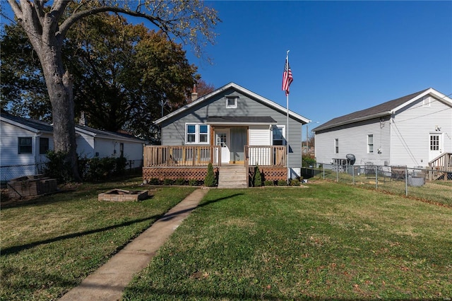 bungalow-style home featuring a front yard, a fire pit, and a deck