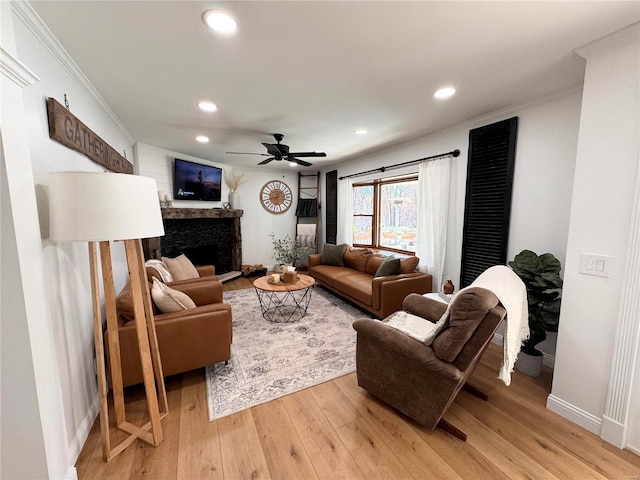 living room featuring ceiling fan, light wood-type flooring, and crown molding