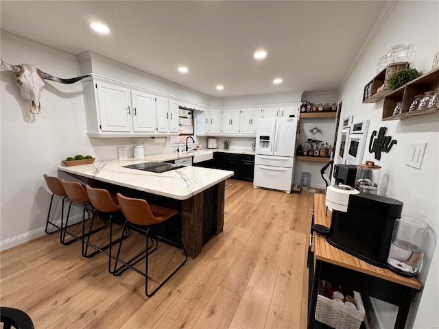 kitchen with white refrigerator with ice dispenser, white cabinets, kitchen peninsula, and light hardwood / wood-style floors