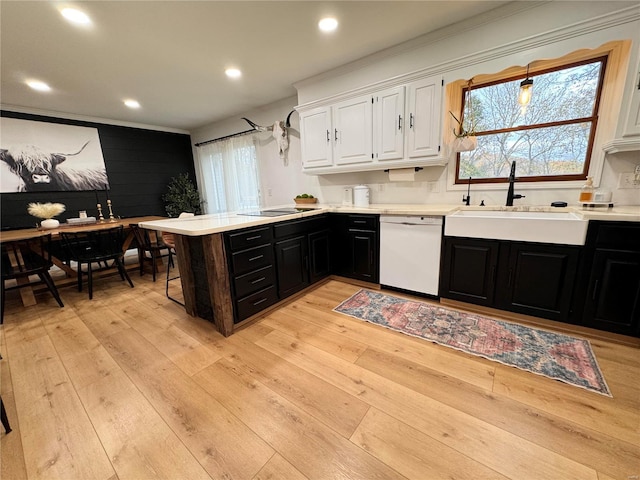 kitchen featuring white cabinetry, sink, hanging light fixtures, light hardwood / wood-style flooring, and white dishwasher