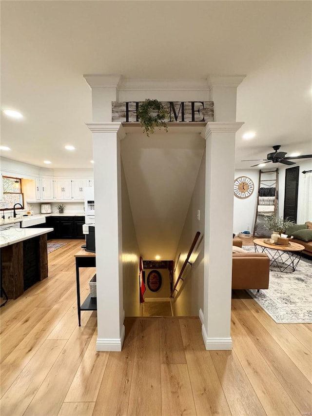 stairway featuring ceiling fan, sink, and wood-type flooring