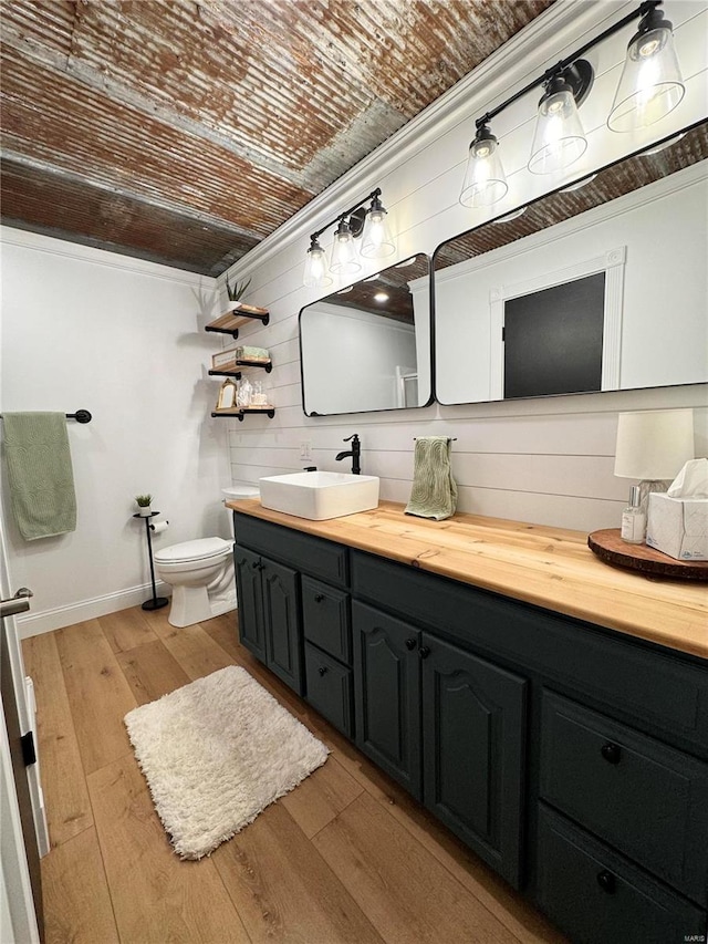 bathroom featuring ornamental molding, vanity, hardwood / wood-style flooring, toilet, and wood walls