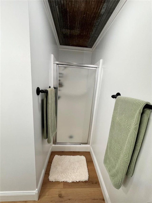 bathroom with wood-type flooring, ornamental molding, and walk in shower