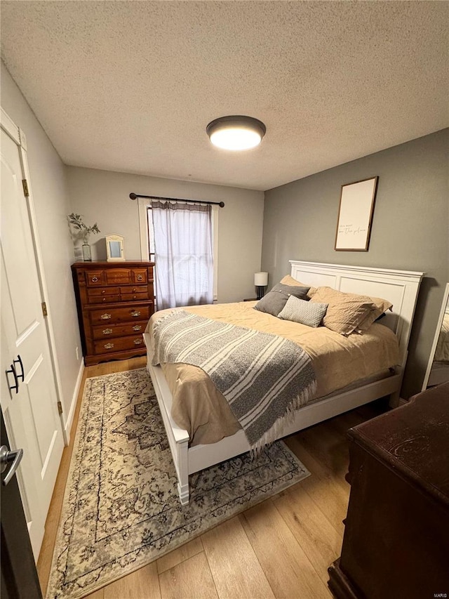 bedroom featuring light hardwood / wood-style floors and a textured ceiling