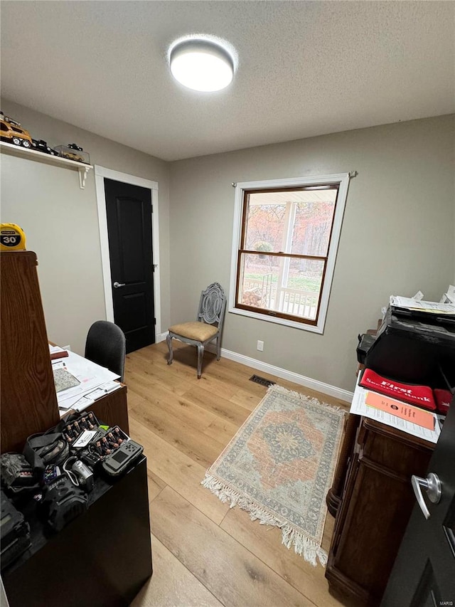 office area with light hardwood / wood-style flooring and a textured ceiling