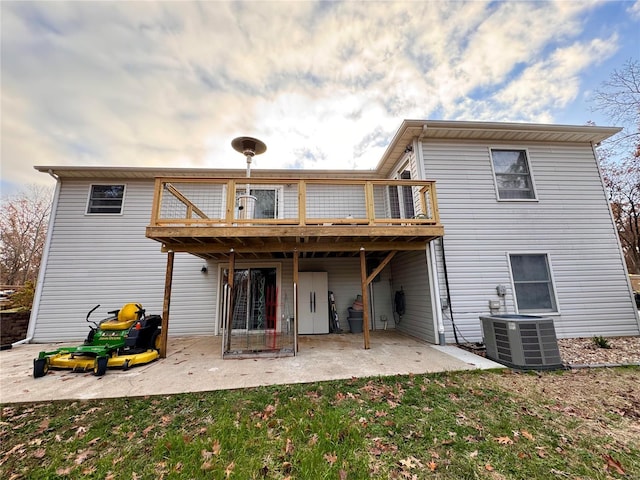 back of property with a balcony, central air condition unit, a patio, and a yard