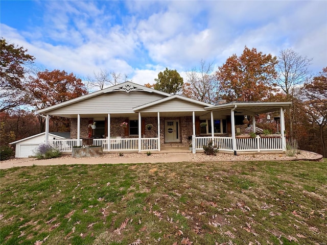 view of front of property with an outbuilding, covered porch, a front yard, and a garage