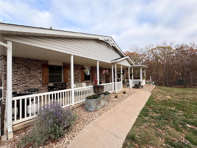 view of side of home featuring covered porch and a yard