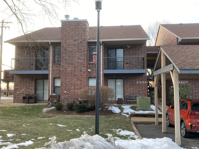 snow covered house featuring a lawn and a balcony