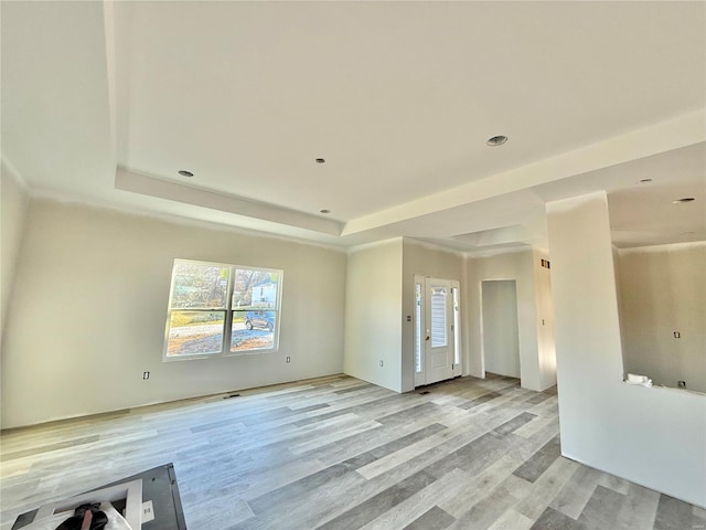 unfurnished living room with a tray ceiling and light wood-style floors