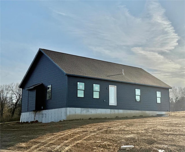 view of side of home with a shingled roof