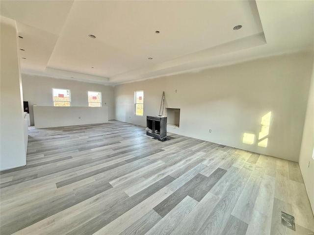 unfurnished living room with a raised ceiling and light wood-type flooring