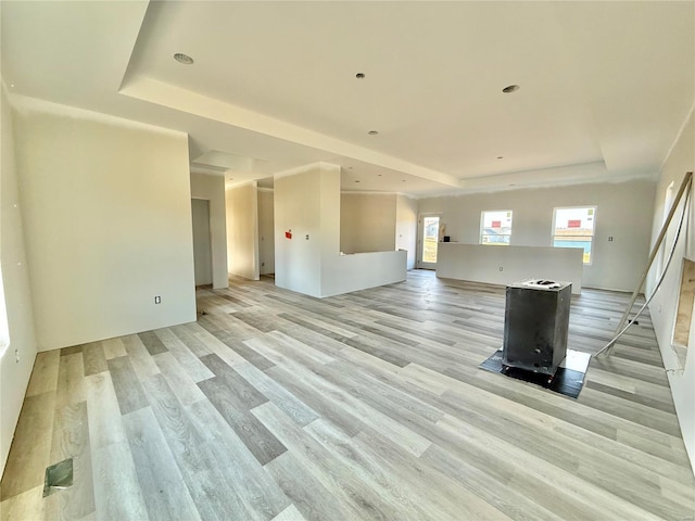 unfurnished living room with a tray ceiling and light wood-style flooring